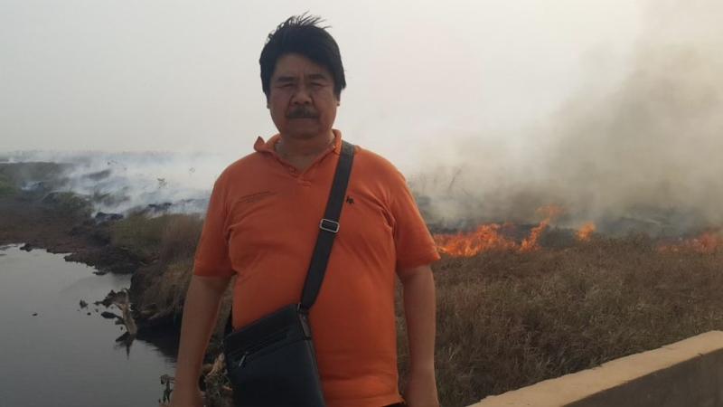 Man stands in front of wildfires