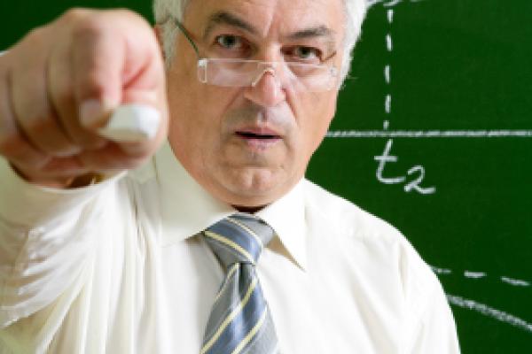 Maths Teacher pointing with chalk at camera