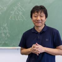 Yu Deng in front of a blackboard