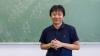 Yu Deng in front of a blackboard